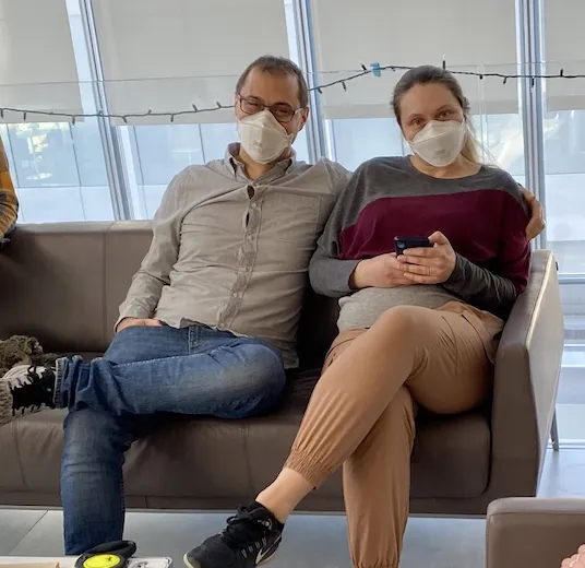 Marco and Lisa are seated, with Marco's arm wrapped around Lisa.