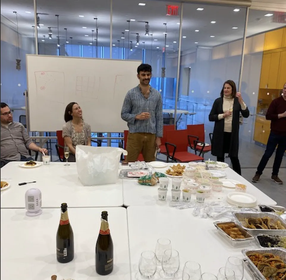 Ariel stands with a champagne glass to toast Albana