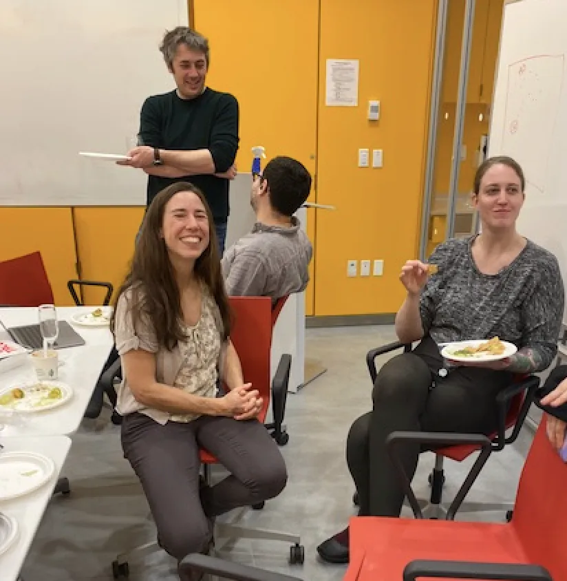 Kevin and Hani talk in the background, while Rachel and Beka sit in the foreground eating lunch. 