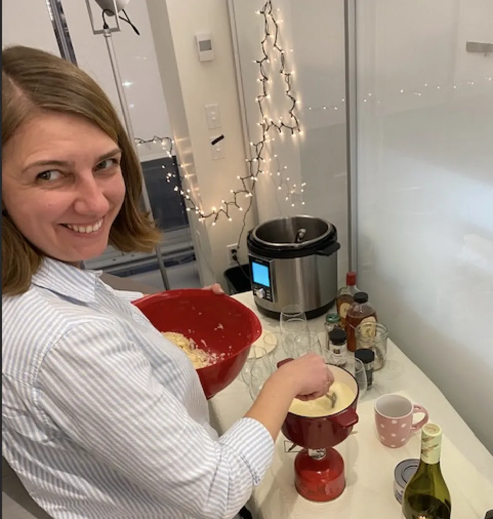 Marianna adding grated cheese into a fondue pot