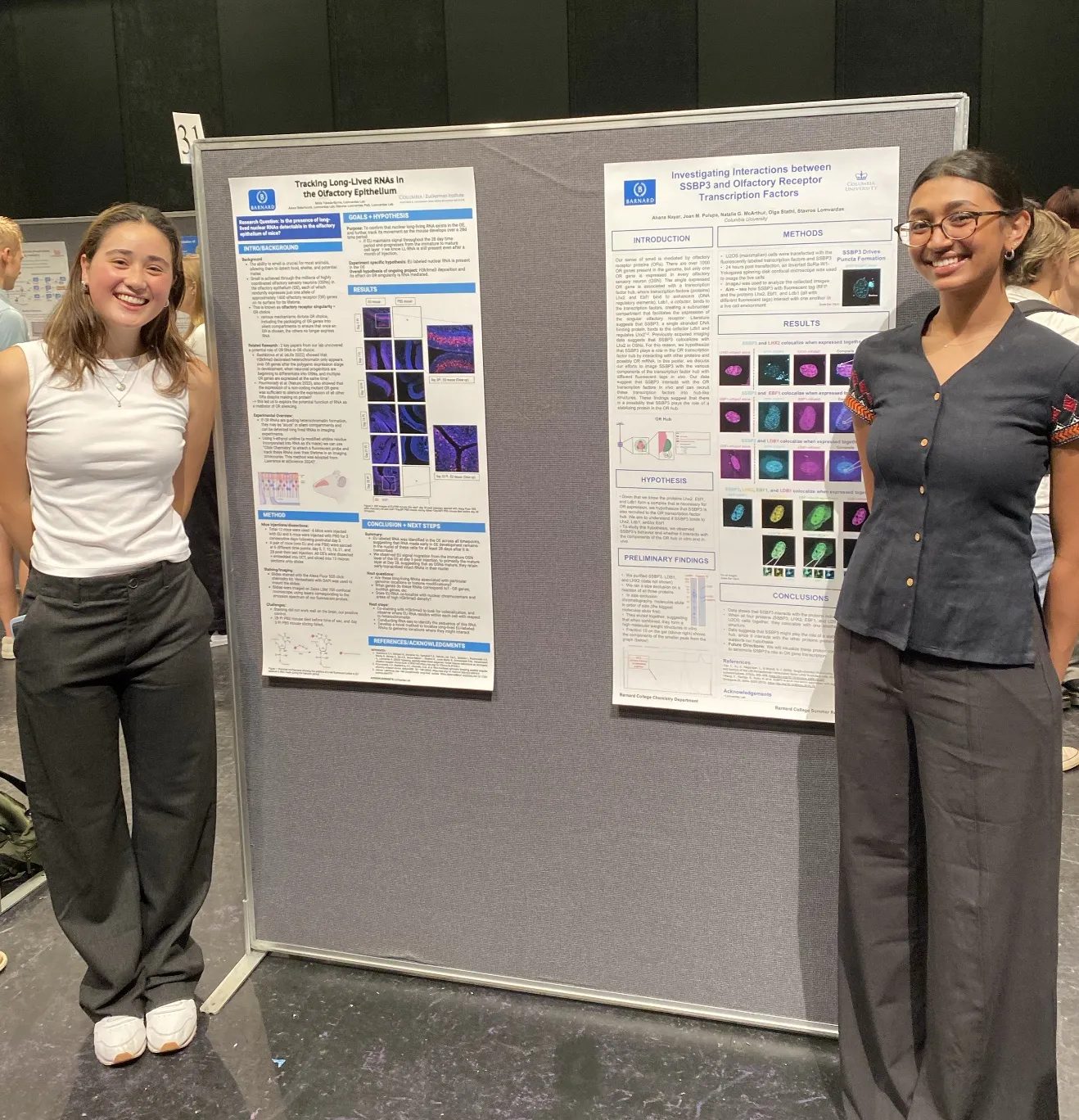 two students stand next to their posters