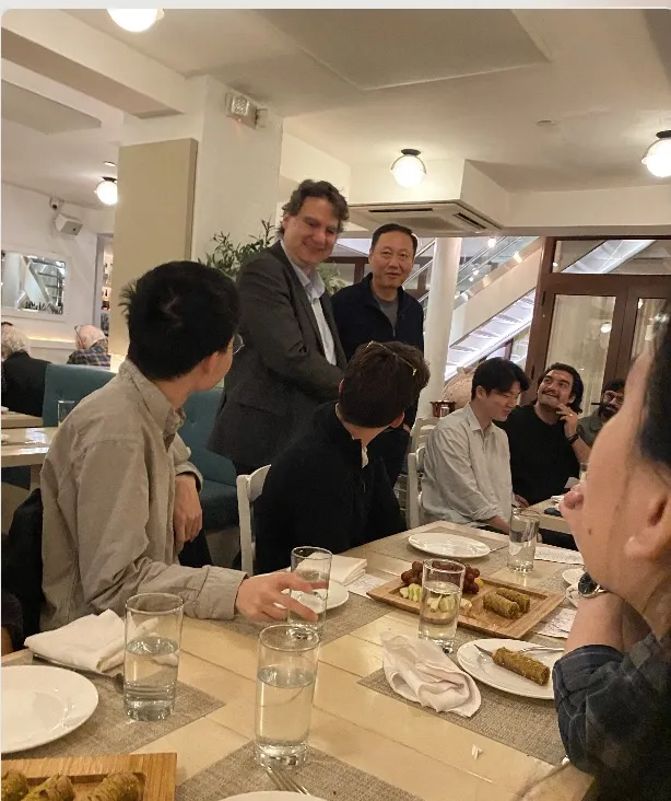 two people standing making a toast to a seated group at a table