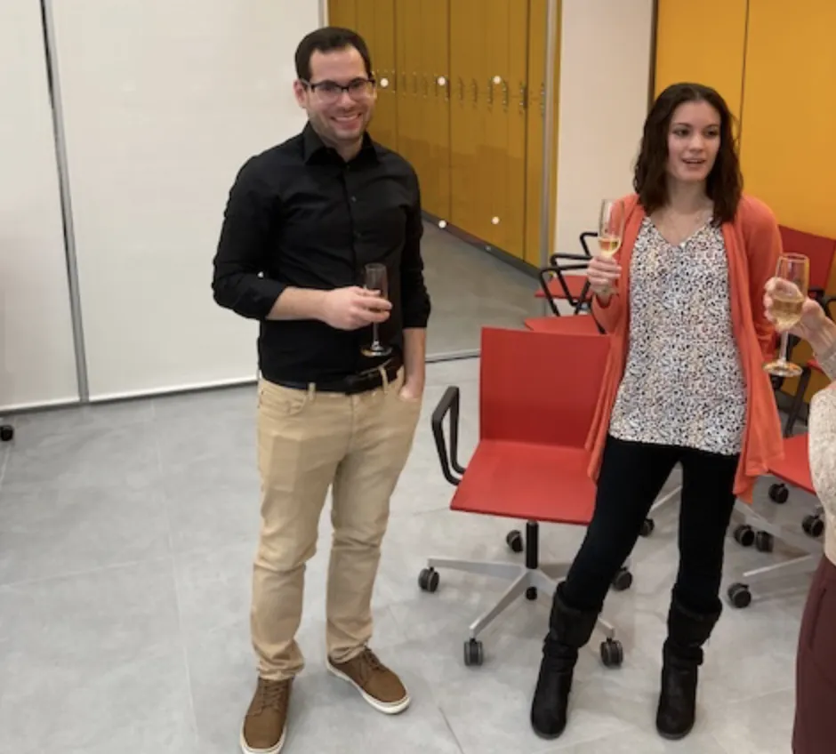 Hani and Emily are standing while drinking champagne