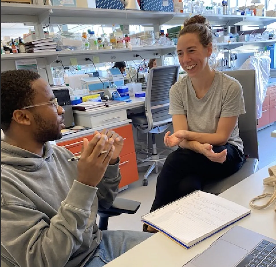 Chastin and mentor, Rachel, discussing their project while sitting at his desk.